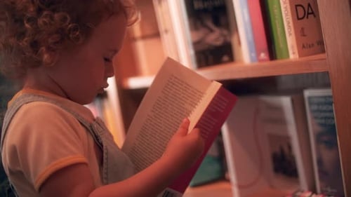 Baby Girl Pretends to Read a Book in the Library