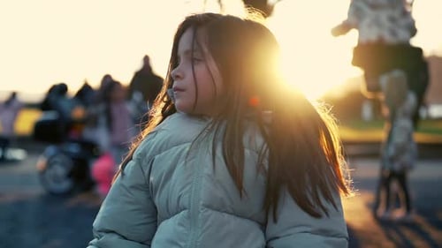 Contemplative Little Girl on Park Bench in Winter Sunset, Blurred Play Background. Backlight of 8