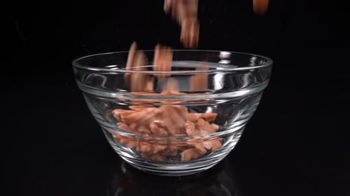 Walnuts Filling Glass Bowl on Black Background