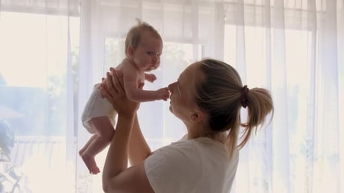 Mother Holds Baby Up to Window Light