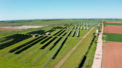 Solar panels in a green field on a sunny day with a clear blue sky, aerial view