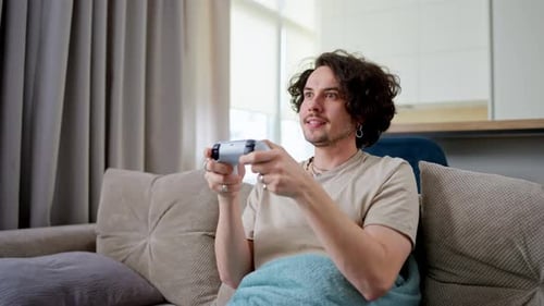 Man Playing Video Game on Couch, Celebrates Success