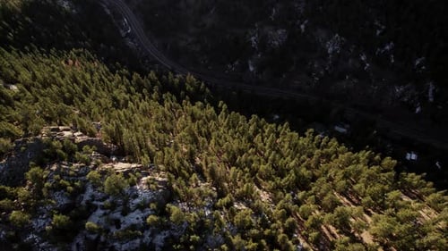 Dramatic Light Flying Over Lush Green Pine Tree Mountain Hillside and Dark Countryside Road In Color