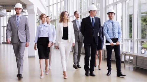 Happy group of architects with blueprint walking at office building construction site