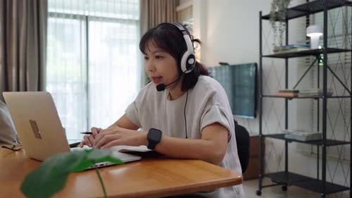 Woman Working on Laptop with Headset at Home