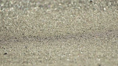Shimmering Wet Sand with Sparkling Bokeh in Bright Sunlight