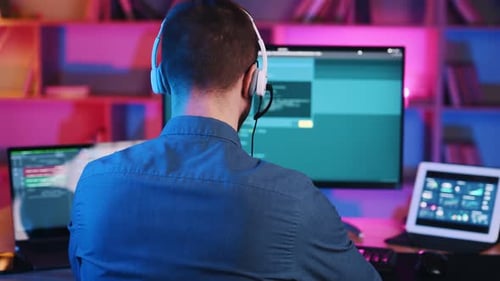 Der Programmierer arbeitet, indem er am Computer sitzt. Neonbeleuchtung