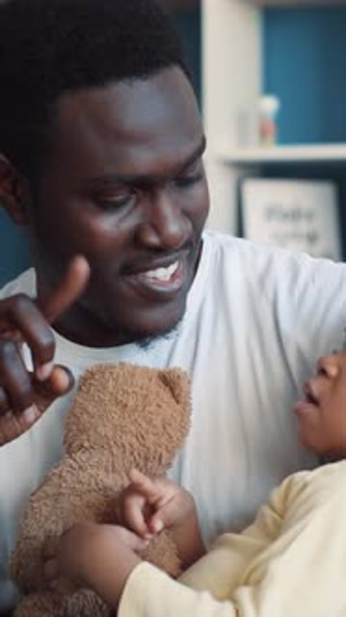 Man Speaking with Child Holding Teddy Bear Indoors