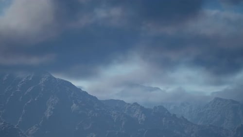 Bewölkter Himmel über felsigen Bergen und grünem Laub