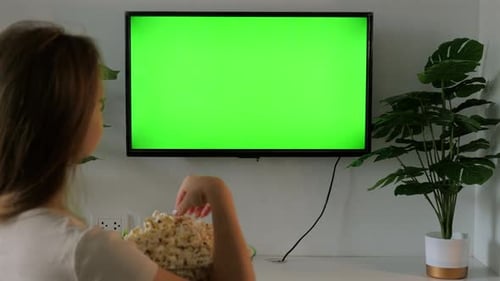 Woman Watching Television with Green Screen While Eating Popcorn at