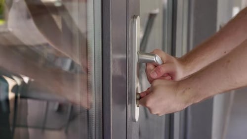 Man Unsuccessfully Trying to Open Locked Door with Broken Lock Turning Key and Pulling Handle