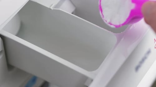 Close-up slow motion shot of hands pouring laundry household washing powder detergent laundry stain