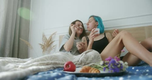 Pareja de lesbianas compartiendo la comida del desayuno en la cama