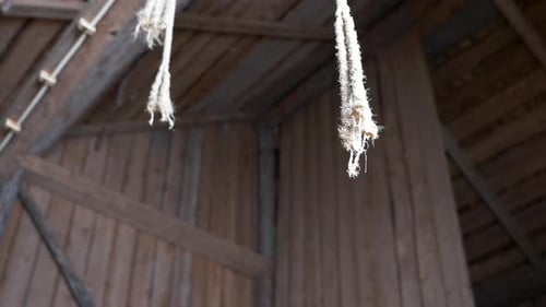 slow orbit shot of rope hanging from ceiling of wooden barn. Concentration camp concept. Low angle.