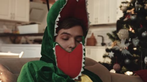 Un gentil garçon en costume de dinosaure se réveillant dans un appartement inconnu après la fête du Nouvel An