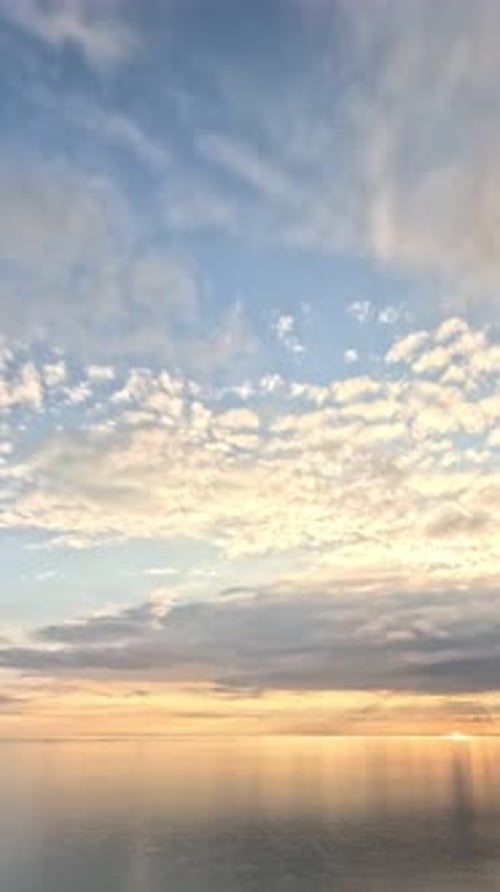 Timelapse : cumulus moelleux se déplaçant dans un ciel doré brillant au coucher du soleil au-dessus de la mer, nature aérienne abstraite