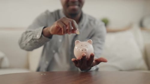 Economy and Finance Young Black Man Saving Money in Piggy Bank Closeup View African American Student