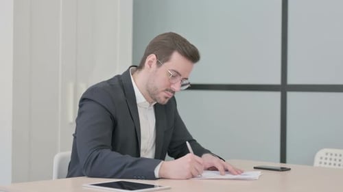 Business Man Completing Paperwork at Office Desk