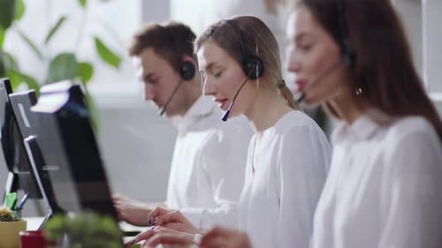 Smiling Call Center Employees Sitting in Line with Their Headset Focus on Pleasant Beautiful Young