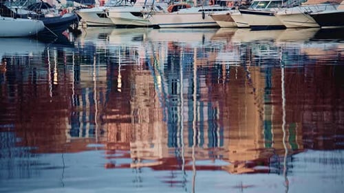 Detailed shot of distorted reflections of buildings and boats on gently moving harbor water
