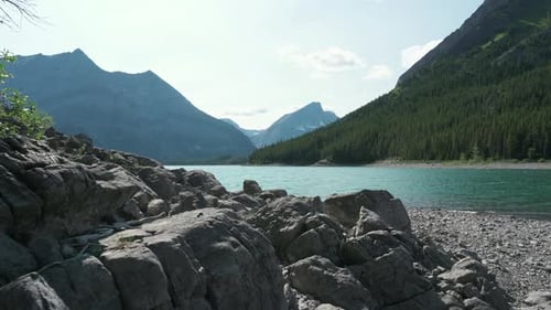 Sunny mountain vista and lake beyond rocky beach in remote tranquil nature