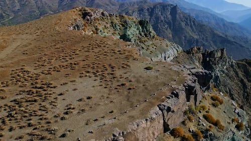 Aerial view of colorful eroded cliffs with sparse vegetation on alpine ridge
