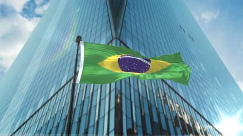 Brazilian Flag Waving in Front of Modern Skyscraper
