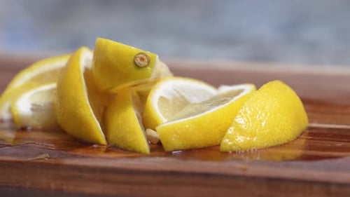 Lemon Wedges Juicy and Yellow Close Up Pan Left on Wooden Cutting Board with Lemon Juice