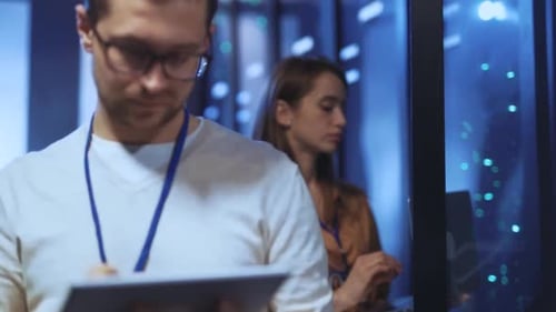 Ein Mann und eine Frau arbeiten bei der Datenanalyse in einem Serverraum zusammen