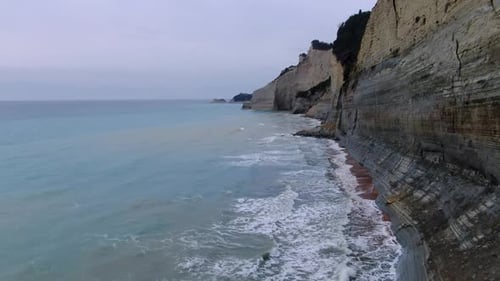 Cinematic drone footage flying along the immense layered cliffs of Loggas Beach, Corfu.