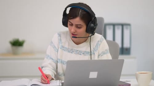 Young Woman Working At Computer With Headset
