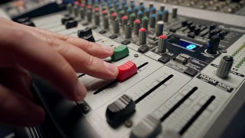 close-up shot of the male hand of a sound engineer switching settings on mixing console recording