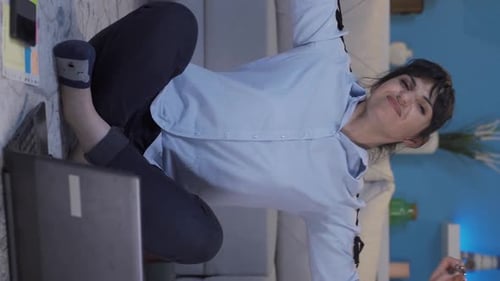 Vertikales Video einer Frau im Home-Office, die gähnt und sich in der Kamera entspannt.