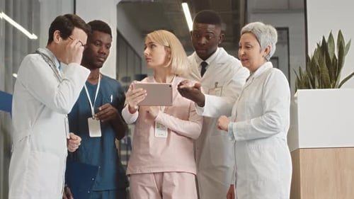 Medical Team Discussing Information on Tablet in Hospital