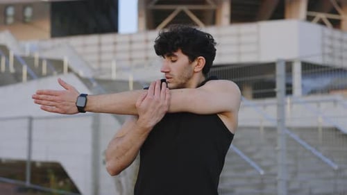 Man Stretches Arms Outside at Stadium