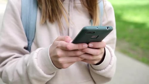 Little School Girl Surfing On Internet With Her Smartphone In Part