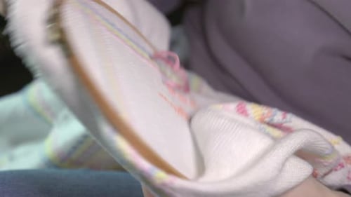 Close-up shot of a hand cross-stitching a blanket and finishing off a stitch