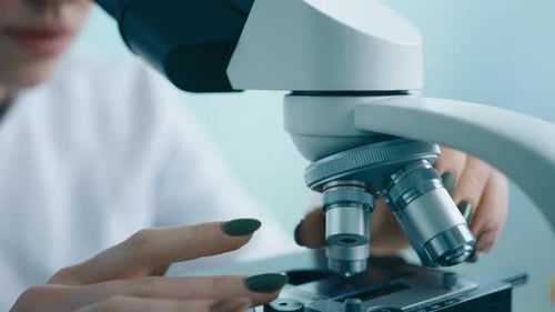 Woman Adjusting Microscope in a Laboratory Setting