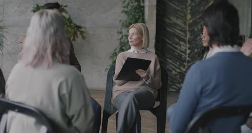 Professional Therapist Talking to Diverse Group of People and Taking Notes Sitting in Circle Sharing