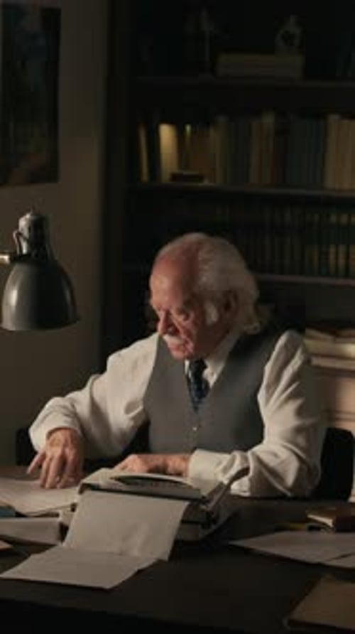 Senior Man Typing at a Desk in Dark Room