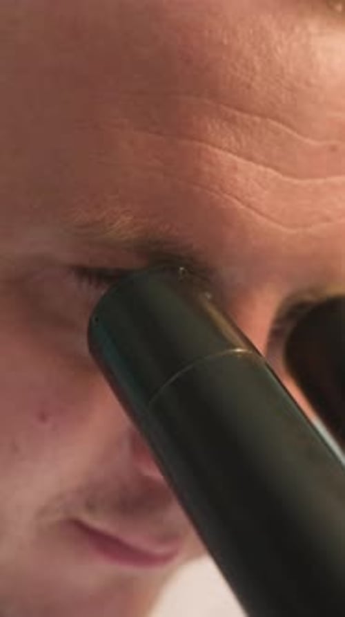 Man Looking Through Microscope in Laboratory Setting