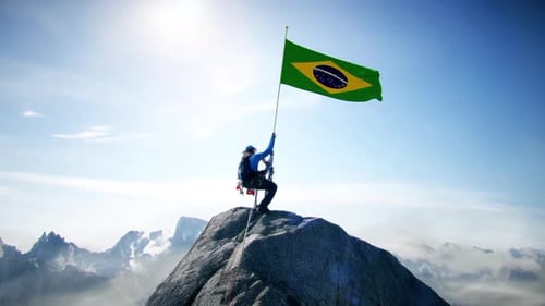 Montañero con la bandera de Brasil en la cima de la montaña