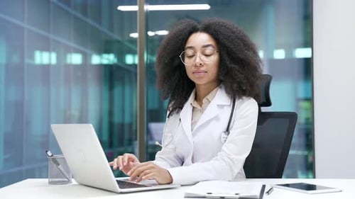Young Doctor Typing on Laptop in Modern Office