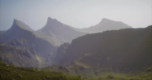 Les montagnes s'élèvent au-dessus de vallées verdoyantes dans un paysage tranquille à l'aube