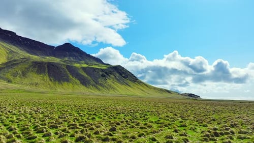 Paisagem panorâmica nas montanhas da Islândia com grama verde na primavera Céu azul com nuvens sobre o