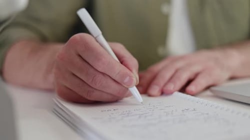 Close Up of Male Hands Taking Notes on Notepad Using White Pen at Home