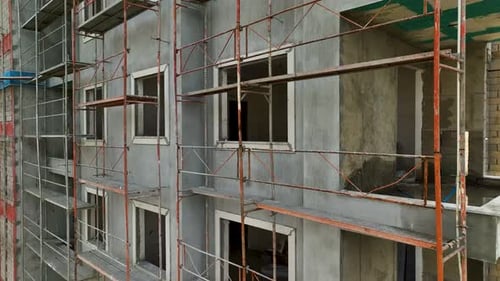 Los constructores trabajan de frente al edificio, se apoyan en el andamio