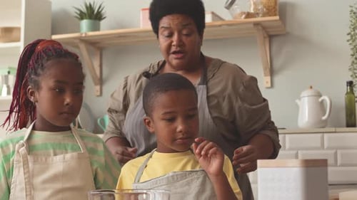 Woman and Children Cooking Together in Kitchen