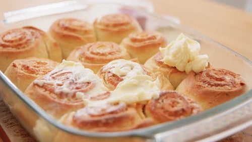 Kulinarisches Konzept zum Backen und Kochen von Speisen - Frau fügt Buttercreme-Topping zu gebackenen Brötchen in...