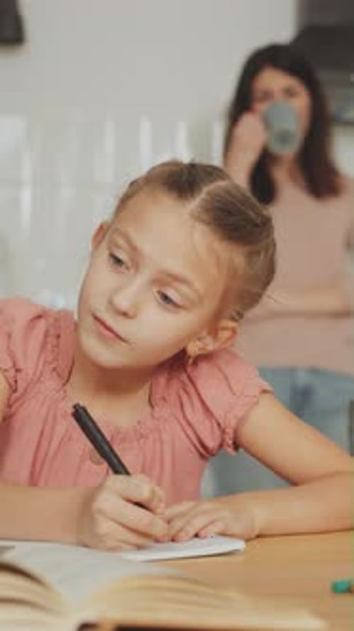 Girl Writes in Notebook While Adult Watches
